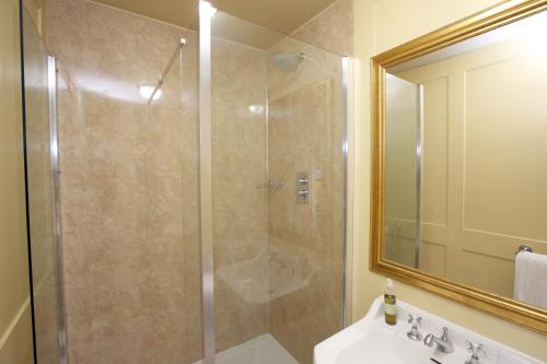 a bathroom with a shower with a sink and a mirror at The Cornmill in Kirkbymoorside