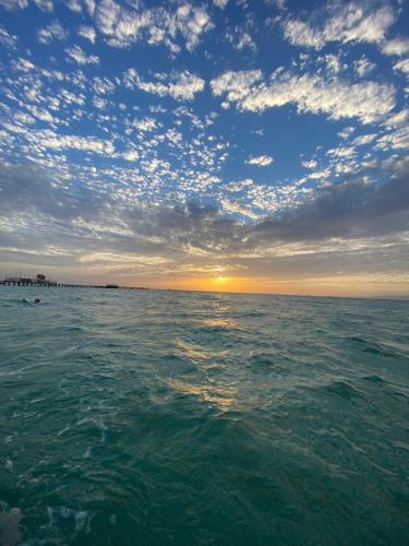 a large body of water with the sun setting at Nozha Beach - Ras Sudr in Ras Sedr