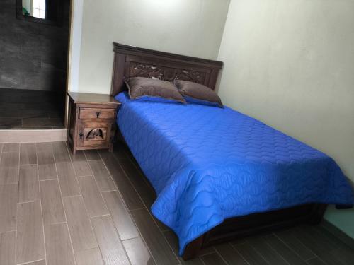 1 cama con edredón azul y mesita de noche en Casa de campo Sueño Amatista, en Gachetá