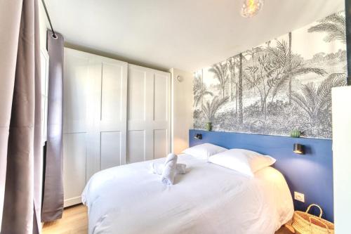 a bedroom with a white bed with a stuffed animal on it at Le Verde - Bel appartement cosy in Saint-Genis-Laval