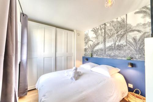 a bedroom with a white bed with a stuffed animal on it at Le Verde - Ravissant appartement cosy in Saint-Genis-Laval