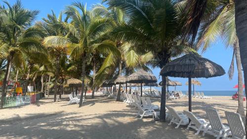 a beach with chairs and umbrellas and palm trees at Punta Centinella Yacht Club in Santa Elena