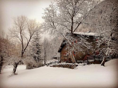 a cabin with snow on the roof and trees at Cozy Chalet next to the Dora Baltea river in Villaret