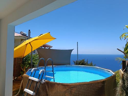 a swimming pool with an umbrella and chairs and a table at Poz Tropicale in Schœlcher