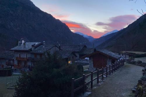 a group of houses in a valley with a sunset at Cozy Chalet next to the Dora Baltea river in Villaret