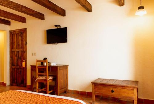 Schlafzimmer mit einem Schreibtisch und einem TV an der Wand in der Unterkunft Hotel Diego de Mazariegos in San Cristóbal de las Casas