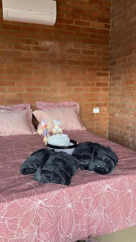 a bed with two pillows and a table on it at Chalé Magia do Serrano in São Bento do Sapucaí
