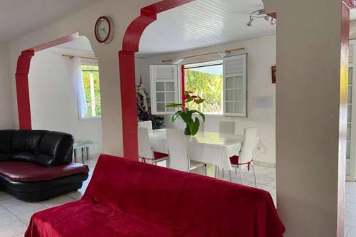 uma sala de estar com um sofá vermelho e uma mesa em VILLA PISCINE PLEIN SUD MARTINIQUE ALIZESDESCAPS em Sainte-Anne