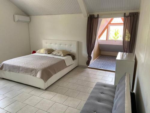 ein Schlafzimmer mit einem großen Bett und einem Fenster in der Unterkunft VILLA PISCINE PLEIN SUD MARTINIQUE ALIZESDESCAPS in Sainte-Anne