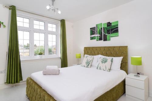 a bedroom with a large bed with green curtains at Barking Haven Retreat - Airport - Parking - Train Station in Barking