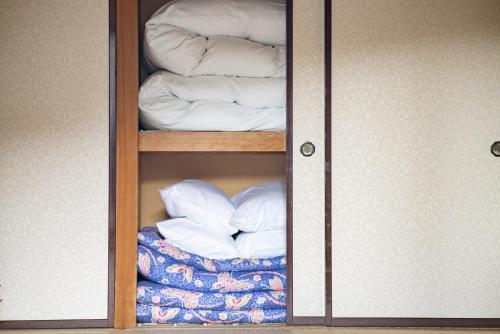 um armário com uma porta de vidro com toalhas e almofadas em Yuzawa House - Vacation STAY 07080v em Yuzawa