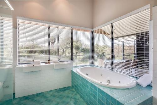 a bathroom with a tub and large windows at Regency Beach Club in Dunsborough