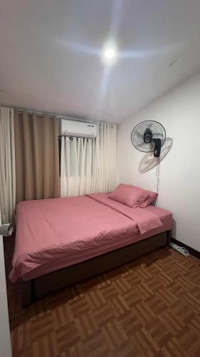 1 dormitorio con 1 cama rosa y ventilador en Orilla Transient 1 en Mabalacat