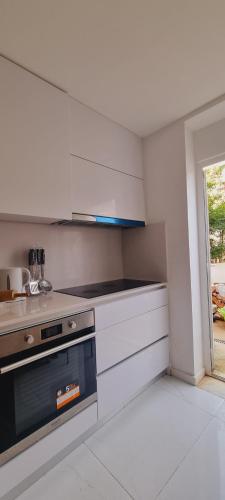kuchnia z białymi szafkami i kuchenką w obiekcie Owls Hostel Ribeiro w Porto