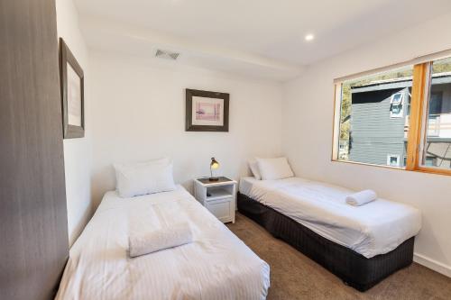 two beds in a small room with a window at Powder 2B in Thredbo