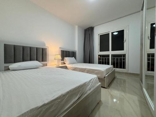 a bedroom with two beds and a window at Luxury Inn: 2BR Prime location in Madinaty B12 in Madinaty