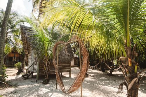 un paio di palme e una panchina nella sabbia di Cabana juriti a Camaçari
