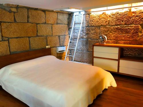 a bedroom with a bed and a stone wall at Casa Boutique Marín 1910 in Marín