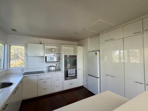 a kitchen with white cabinets and a white refrigerator at Super large seaview house in Wellington