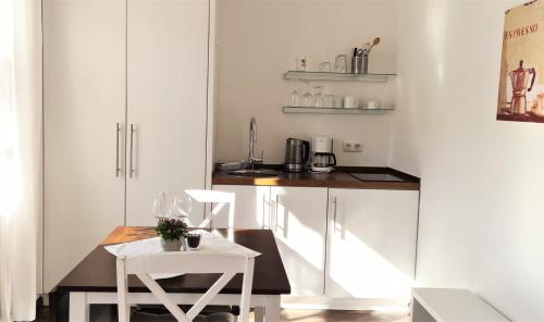 una pequeña cocina con armarios blancos, mesa y sillas en Gästehaus Sieger-Brandner Apartment im Gästehaus Sieger-Brandner, en Ramsau