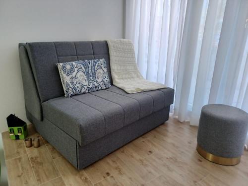a gray couch in a living room next to curtains at ZIL - Studio Apartment City Center in Zagreb
