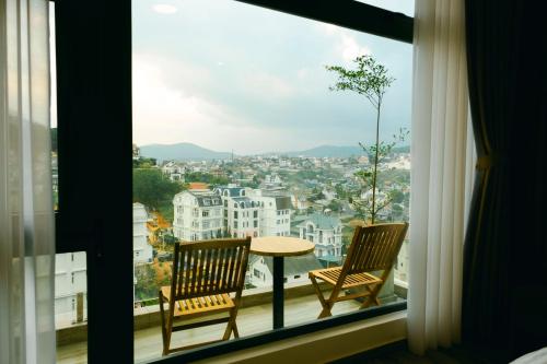 ein Fenster mit 2 Stühlen und einem Tisch auf dem Balkon in der Unterkunft Lộc Nguyên Hotel Dalat in Xuan An