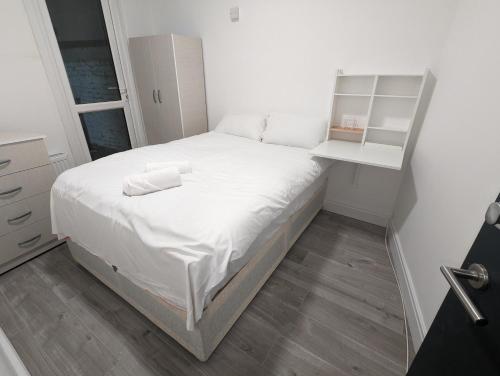 ロンドンにあるMile End Roomsの小さなベッドルーム(白いベッド1台、棚付)