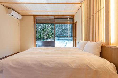 a bedroom with a large white bed in front of a window at プライベートリゾート犬の日 in Hakone