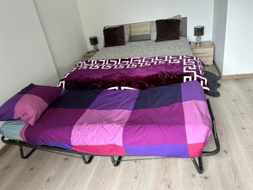 Ce lit se trouve dans un dortoir doté de draps violets et violets. dans l'établissement Le bonheur 1 & 2 parking et wifi gratuits, à Charleroi