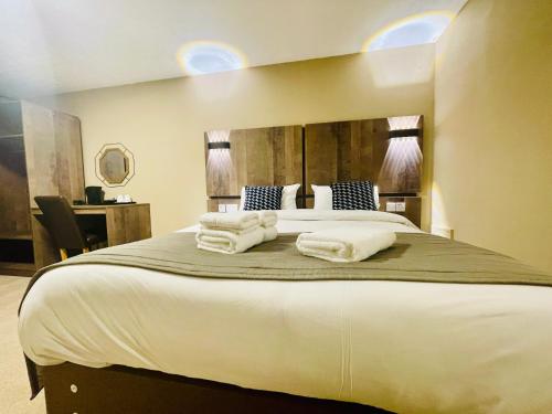 a bedroom with a large bed with towels on it at Hylands Hotel in Coventry