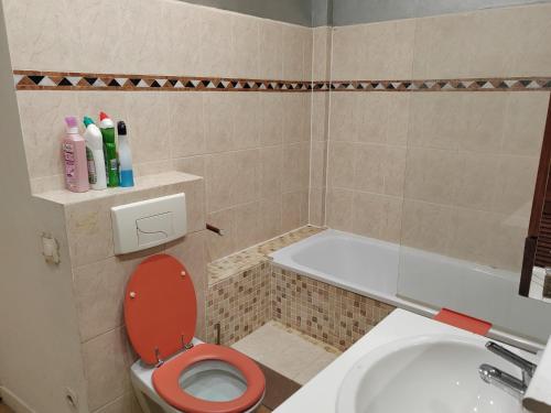 La salle de bains est pourvue de toilettes rouges et d'une baignoire. dans l'établissement Lovelyottoman in Paris, à Longjumeau