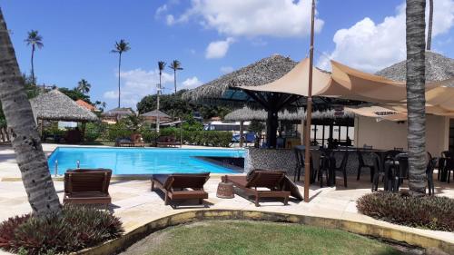 a pool at a resort with chairs and umbrellas at Eco Paradise ap 122 in Cumbuco