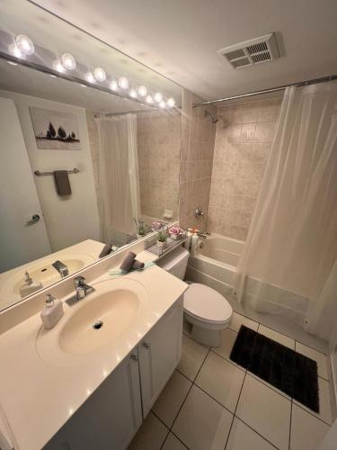 a white bathroom with a sink and a toilet at Downtown Toronto Suite By The Lake in Toronto