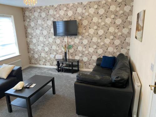 Oasis Abode @ Ashover Newcastle في Kenton: غرفة معيشة مع أريكة وتلفزيون على الحائط