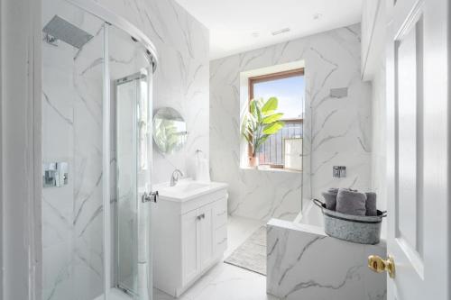 a white bathroom with a shower and a sink at Le Nomade MTL in Montréal