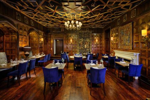 a dining room with tables and blue chairs and a chandelier at Delta Hotels by Marriott St Pierre Country Club in Chepstow