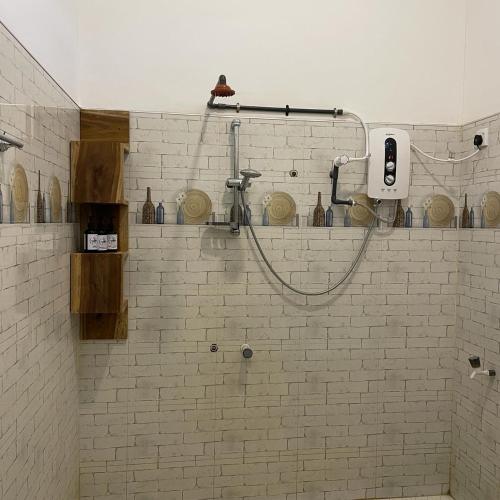 a shower in a bathroom with a white brick wall at Agra Arugambay in Arugam Bay