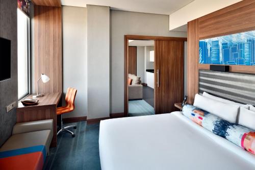 リヤドにあるAloft Riyadh Hotelのベッドとデスクが備わるホテルルームです。