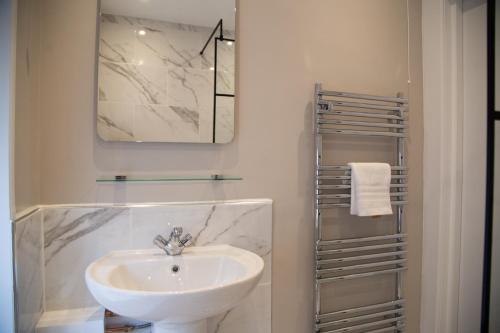 La salle de bains blanche est pourvue d'un lavabo et d'un miroir. dans l'établissement 1 The Bookies Modern Apartment, Central Location, à Scarborough