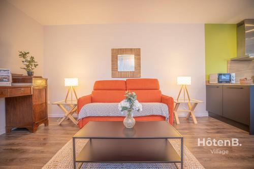 un salon avec un canapé orange et une table dans l'établissement The Chinchauvaud Cosy - Oasis of Freshness in the Heart of the City, à Limoges