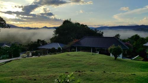 a house on a hill with fog in the distance at Ranis Lodge in Kampung Padang Masirat