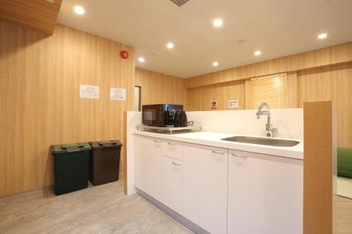 a kitchen with a sink and a counter with a microwave at OHWA hostel minowa station in Tokyo