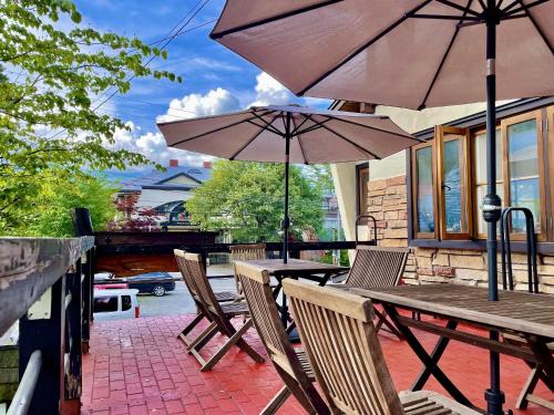 a table and chairs with umbrellas on a patio at Pension Eastmountain Hakuba in Hakuba