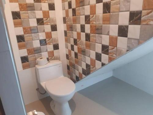 a bathroom with a toilet and a tiled wall at Casa Privada de Estreno con Piscina en Ica in Ica