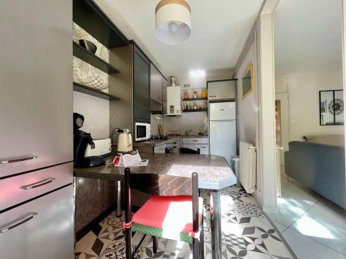 une cuisine avec un comptoir et un tabouret rouge dans l'établissement Appartement T2 lumineux près des Thermes, calme et confort, 2 étoiles, avec balcon et parking - FR-1-503-71, à Balaruc-les-Bains
