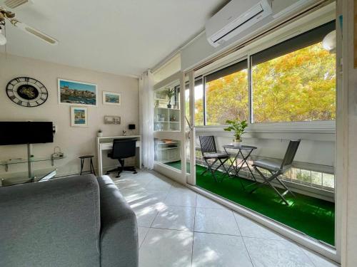 un salon avec un canapé et une grande fenêtre dans l'établissement Appartement T2 lumineux près des Thermes, calme et confort, 2 étoiles, avec balcon et parking - FR-1-503-71, à Balaruc-les-Bains