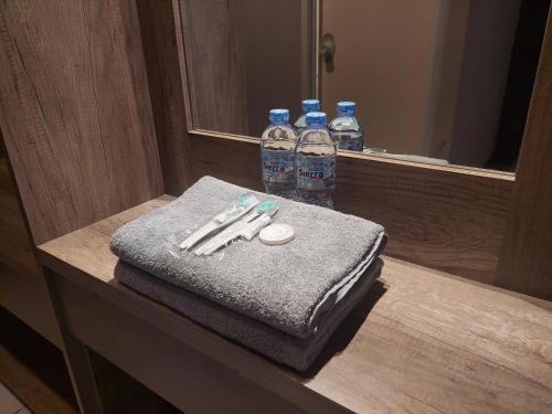 a bathroom counter with two bottles of water and towels at Emerald Apartel in Bandung