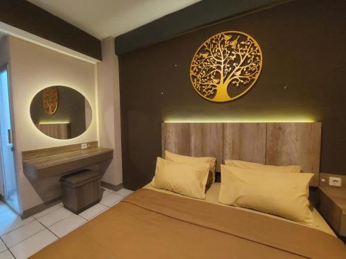 a bedroom with a bed with a tree on the wall at Emerald Apartel in Bandung