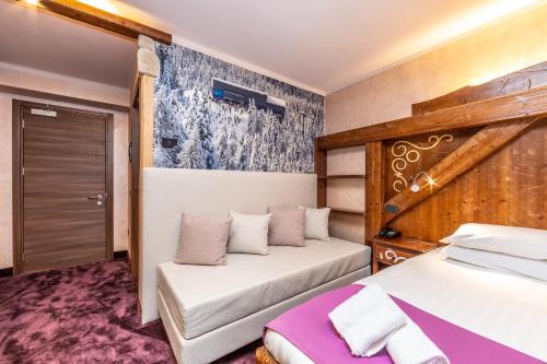 a bedroom with two beds and a couch at Garden Wellness Hotel S in Andalo