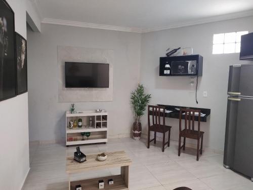 een woonkamer met een televisie en een tafel bij Solares le Bien apartamento proxímo a praia in Búzios